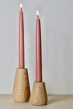 Load image into Gallery viewer, Beautiful hand-turned natural ash candlestick holder, in a small and medium size, showed with a lit Rose Pink Dinner candle in each holder. You can see the grain of the wood in the soft curved shape of each holder.
